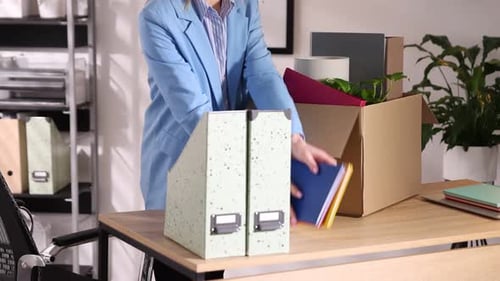 Despido. Mujer empacando sus objetos personales en una caja de cartón en la mesa de la oficina, primer plano