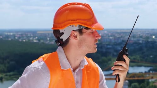 Construction Worker Communicates with Walkie-Talkie on Rooftop