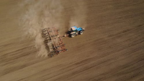 Aerial Footage of Modern Blue Tractor Plowing Dry Field Before Sowing Crops