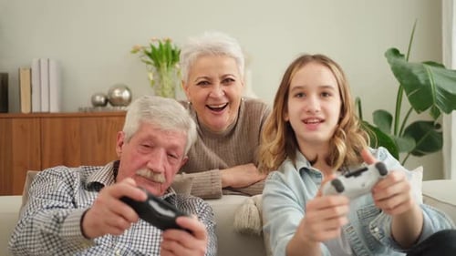 Grandparents and Granddaughter Playing Video Games Together Indoors