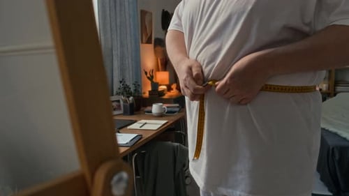Adult Measuring Waist in Bedroom with Measuring Tape