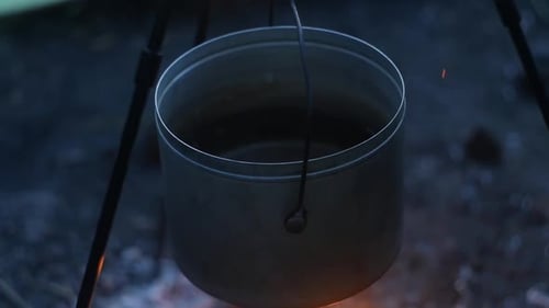 Middle frame of pan with water over the fire on a tripod