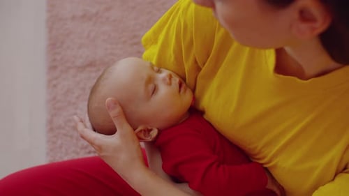 Mother Holds Sleeping Baby Gently Indoors