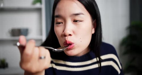 Woman Eating with a Spoon at Home