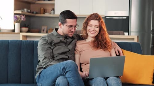 Happy Couple Using Laptop on Blue Sofa