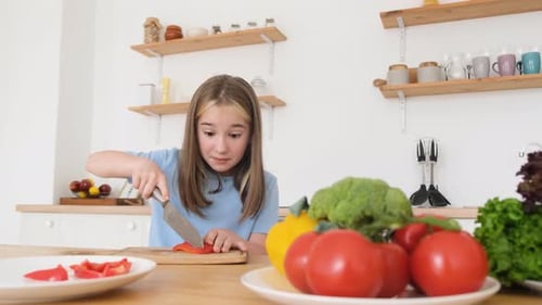 A Little Girl is Preparing a Salad From Fresh Vegetables Breakfast Before Class at School