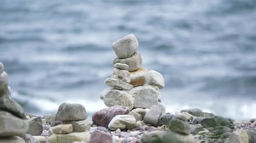 Zen meditation background - balanced stones stack close up on a rocky sea beach surrounded by beauti