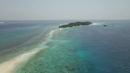 Drone flying towards a tropical island in a atoll in maldives