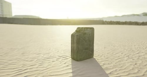 Black Container on Sandy Beach During Sunrise with Soft Light Reflections