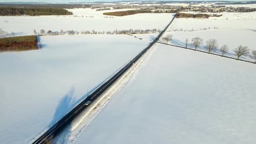 Aerial view of a road with passing cars in a winter landscape covered with snow