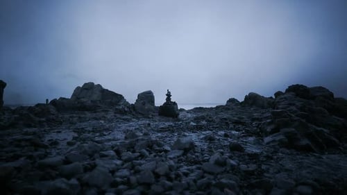 Dark Coastal Landscape with Rock Formations and a Solitary Figure on the Shore