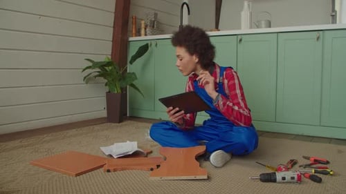 Preciosa mujer negra con tableta viendo un Vídeo tutorial para armar muebles