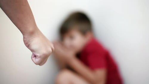 Close view of an adult's fist and scared child on the background