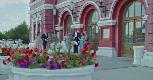 Elegant Group in Formal Wear Gathering Outside Building