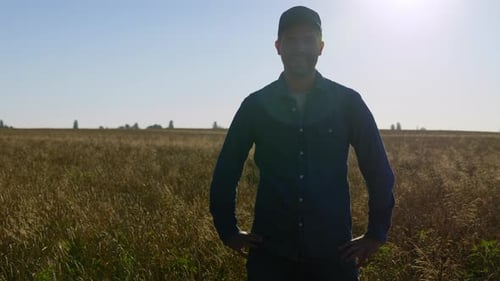 Portrait d'un homme d'affaires fermier souriant debout dans un champ de blé à Sunrise Farming