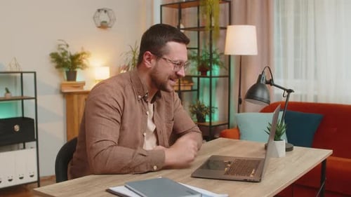 Smiling Young Man Freelancer Having Video Call Via Laptop Sitting at Home Office Desk in Living Room