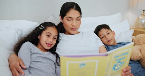 Mother Reading Book with her Children in Bed