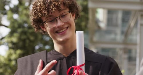 Quando o apresentador estende o diploma com fita, graduado do sexo masculino estendendo a mão, segurando o boné e sorrindo no campus