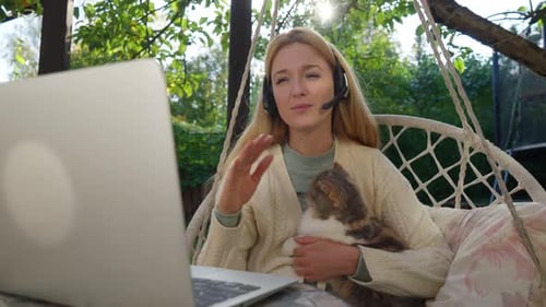 Woman in Garden Hanging Chair Video Call with Cat