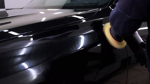 A Car Mechanic Polishing a Black Car Wash Wax and a Polishing Machine
