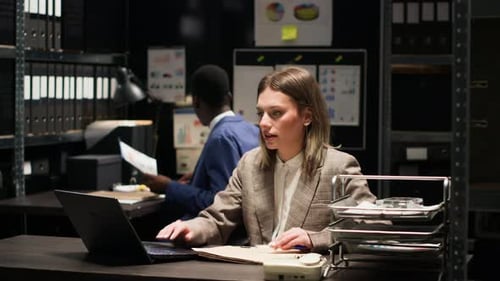 Woman Reviews Documents in Dark Office Environment