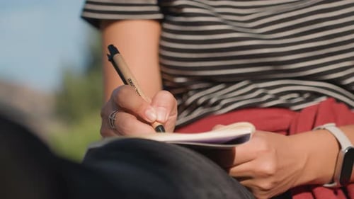 Woman Writing in a Notebook in Nature