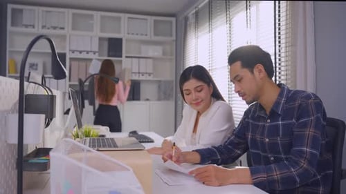 Young attractive businessman and businesswoman work in office workplace.