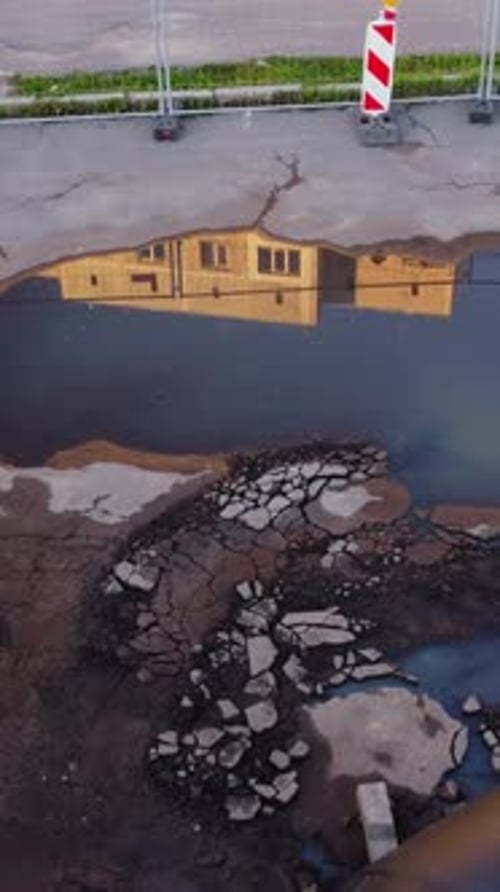 Pothole Filled Road with Building Reflection, aerial view