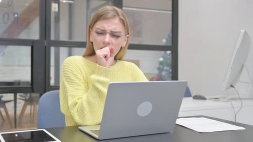 Woman Coughing While Using Laptop at Office Desk
