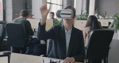 Young Woman Using Virtual Reality Glasses Moving Hands Sitting at Desk in Coworking Office