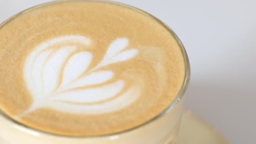 a Cup of Late Coffee with Flower Shape Design on Top at Cafe