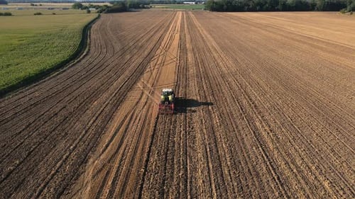 Tractor working on agricultural field, plowed farmland
