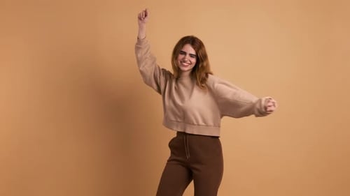 Smiling Woman Dancing with Energy Against Neutral Backdrop