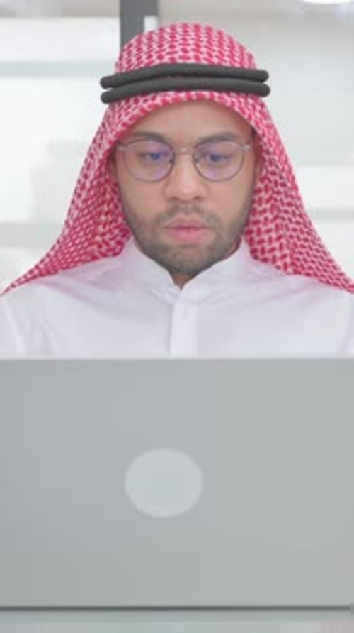 Man in Keffiyeh Works on Laptop in Office