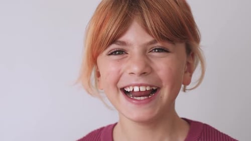 Nahaufnahme-Porträt Gesicht eines glücklichen kaukasischen Mädchens in der Grundschule, blondes, rothaariges Ingwerhaar, lächelnd