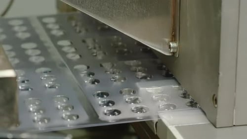 Leere Pillen aus Blisterpackungen, die sich entlang des Förderbandes bewegen, durchsichtige Kunststofffolien mit Zellen
