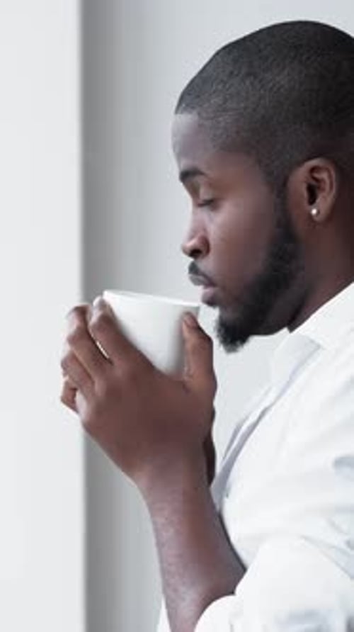 Man Drinking Coffee and Looking Out Window