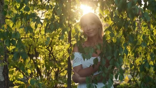 Caucasian Woman Posing Looking at Camera Near Leaves During Sunset
