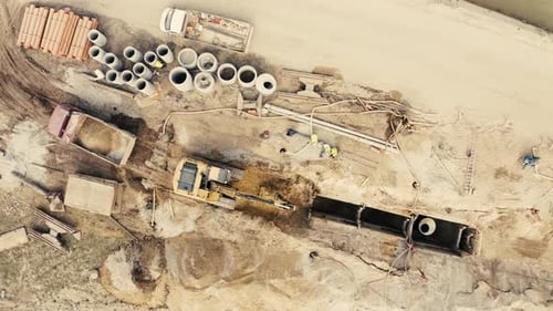 Aerial view of excavator pours sand into the truck. On the construction site top view. Shooting from