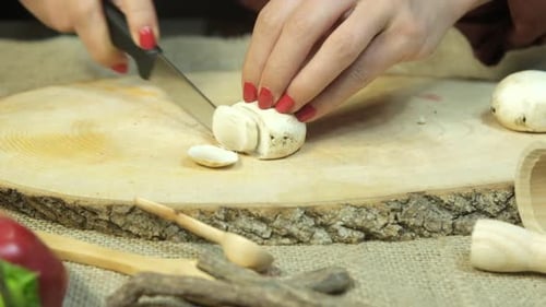 Hands Cutting Mushroom on Wooden Board