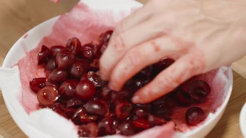 Hands Sorting Pitted Cherries in a Bowl