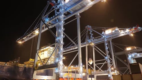 Cranes Moving Cargo at Night in a Shipping Port