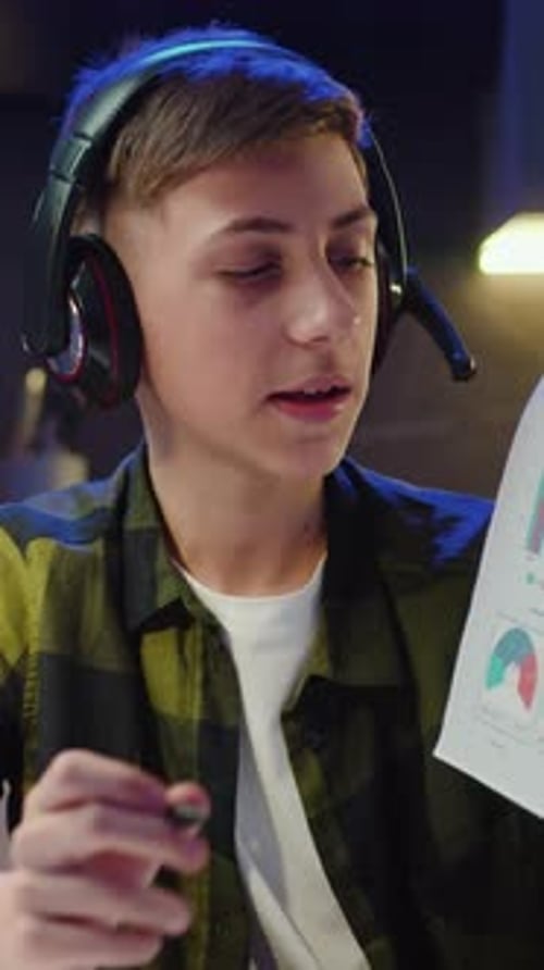 Teenager Male Blogger at Home in the Kitchen Writes a Blog on a Smartphone Boy Showing Graphs and