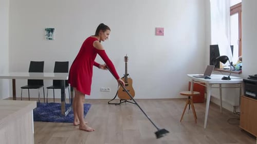 Young Woman Sweeping Floor in Sunny Apartment