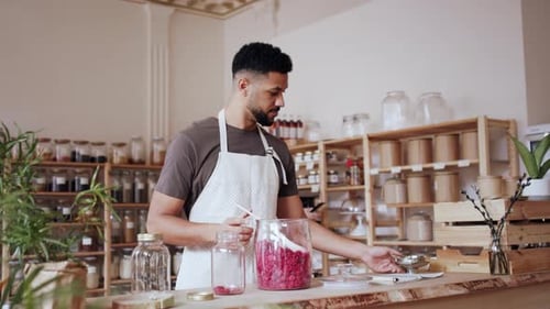 Young Man Filling Jar by Dryed Raspberries in Zero Waste Shop