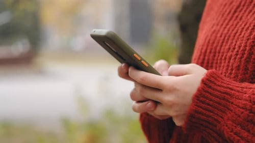 Woman Typing on Smartphone in an Urban Park