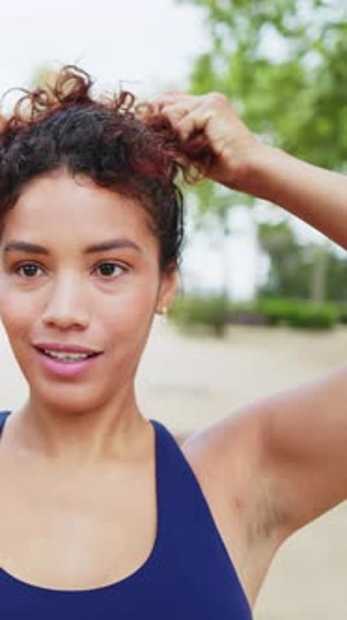 Woman Styles Curly Hair in Natural Outdoor Setting