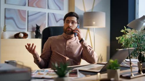 Man Talking on Phone at Desk in Office