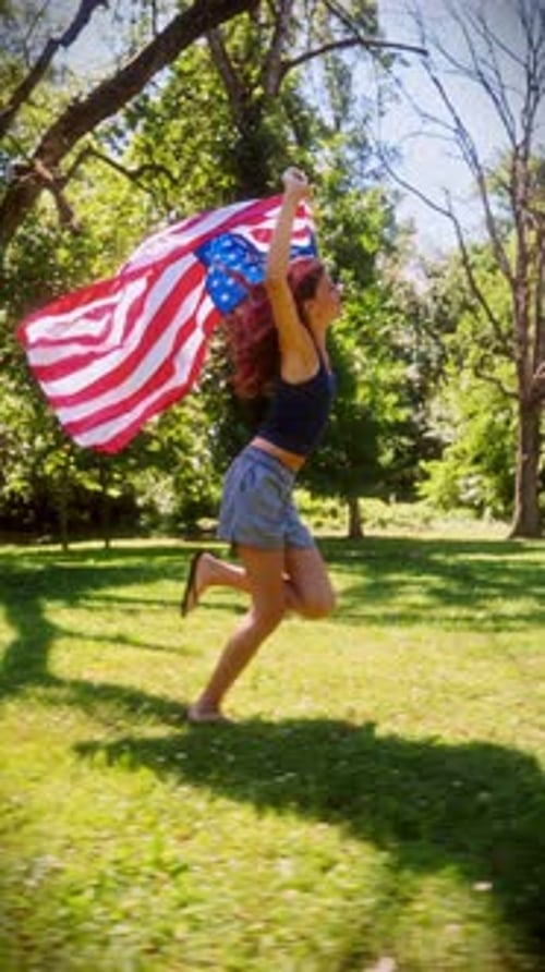 Young Woman Runs with American Flag in Sunny Park