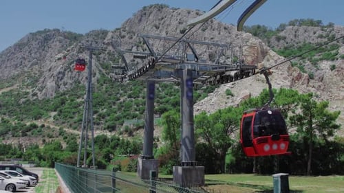 Red Gondolas Ascending Towards a Green Mountain
